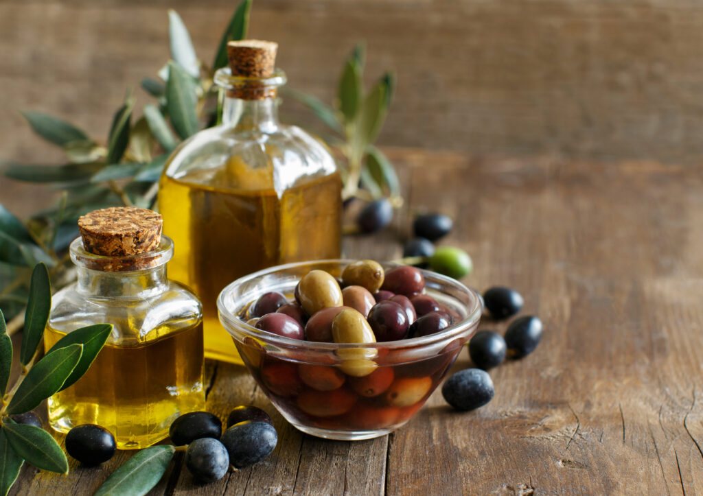 Olive oil and olives on wood background
